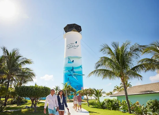 A couple posing in front of a lighthouse surrounded by palm trees.