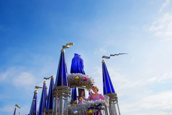 Upward angle view of Disney characters standing in front of a castle's towers.