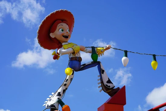 A statue of Jessie from Toy Story holding up one end of a string of lights.